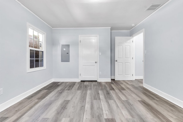 empty room with baseboards, wood finished floors, visible vents, ornamental molding, and electric panel