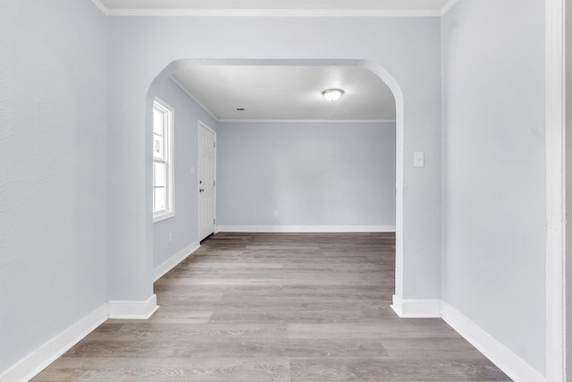 interior space featuring arched walkways, ornamental molding, and wood finished floors