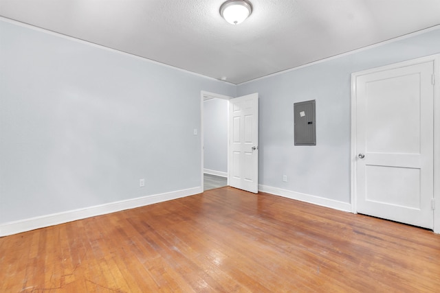 empty room featuring baseboards, light wood finished floors, and electric panel