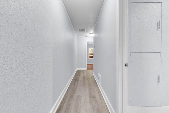 hall with baseboards, visible vents, attic access, and light wood-type flooring