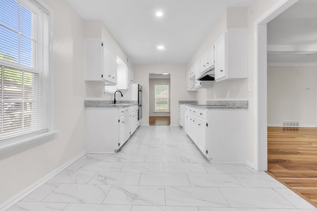 kitchen featuring baseboards, visible vents, a sink, and marble finish floor