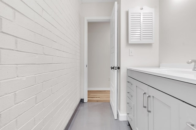 bathroom featuring vanity and brick wall
