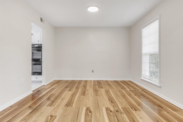 empty room with baseboards, visible vents, and light wood-style flooring