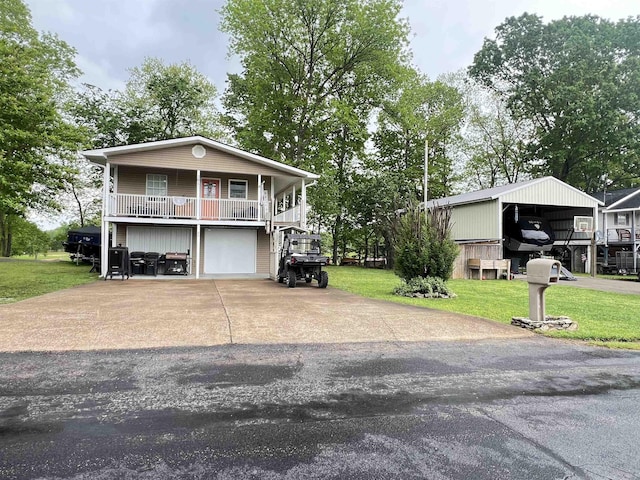 view of front of property with a garage, a detached carport, aphalt driveway, covered porch, and a front yard