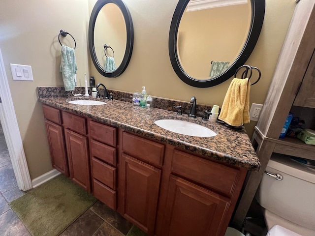full bathroom featuring double vanity, a sink, and toilet