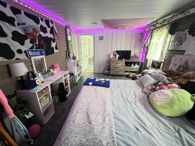 bedroom with wooden walls and concrete flooring