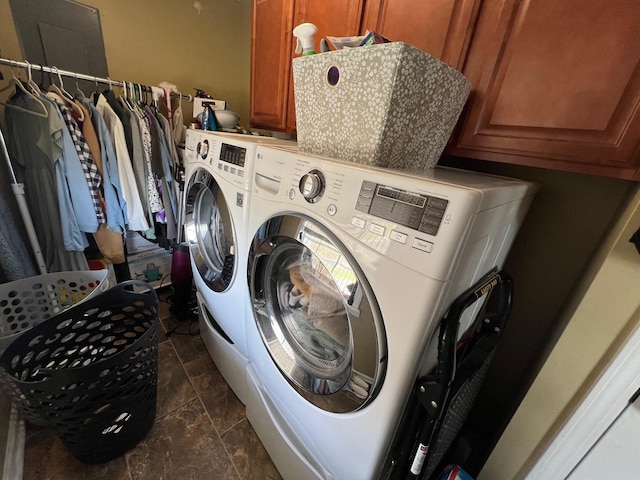 laundry room with cabinet space, washing machine and dryer, and stone finish floor