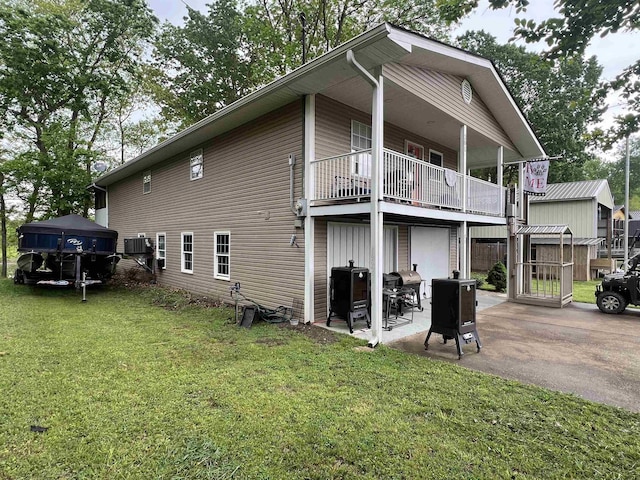 back of house with a lawn, a balcony, central air condition unit, and driveway