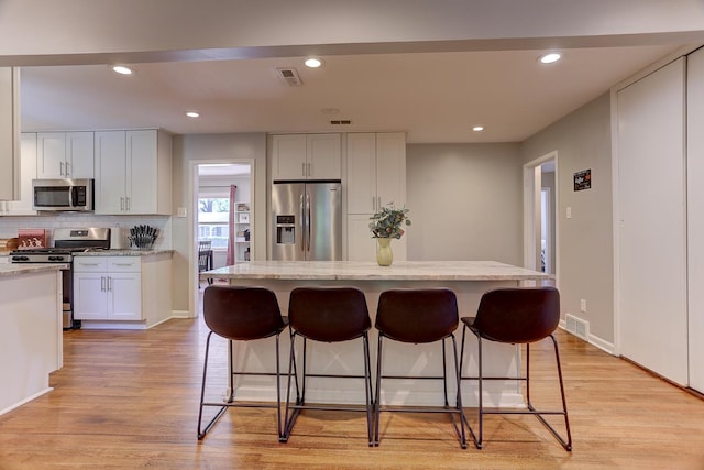 kitchen with visible vents, appliances with stainless steel finishes, and a breakfast bar