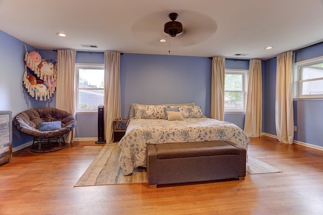 bedroom featuring visible vents, a ceiling fan, baseboards, and wood finished floors