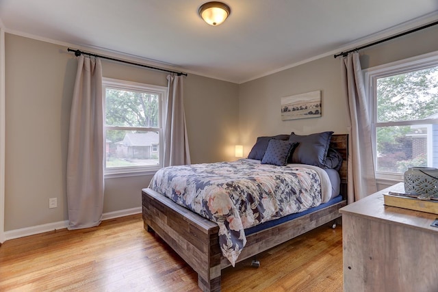 bedroom featuring crown molding, light wood-style floors, and baseboards