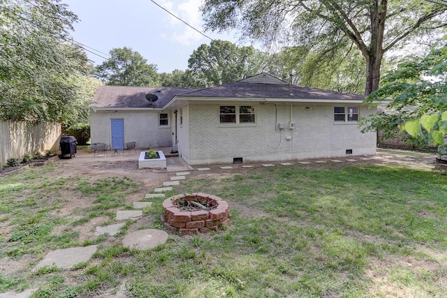 rear view of property with a fire pit, fence, a patio, brick siding, and a lawn