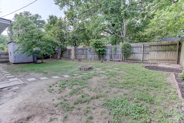 view of yard featuring a fenced backyard, an outdoor fire pit, a shed, and an outbuilding