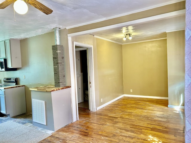 kitchen featuring visible vents, stainless steel range with electric stovetop, hardwood / wood-style floors, baseboards, and ceiling fan