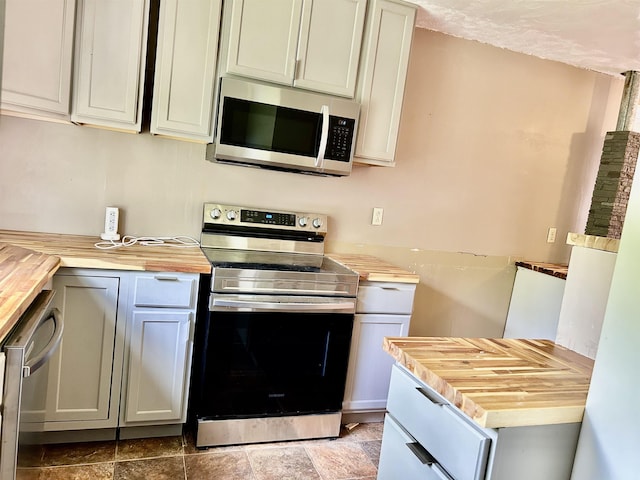 kitchen featuring butcher block countertops, appliances with stainless steel finishes, and stone finish floor