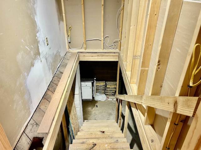 stairway featuring unfinished concrete flooring