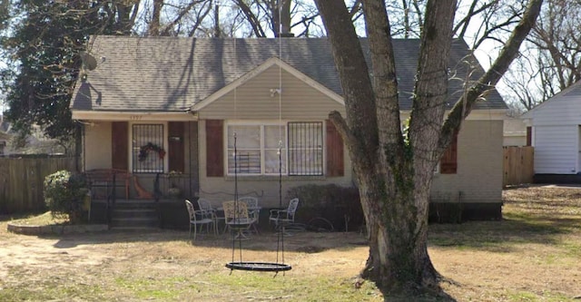 view of front facade featuring fence and a shingled roof
