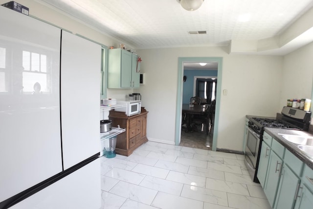 kitchen featuring stainless steel range with gas cooktop, baseboards, marble finish floor, and white microwave