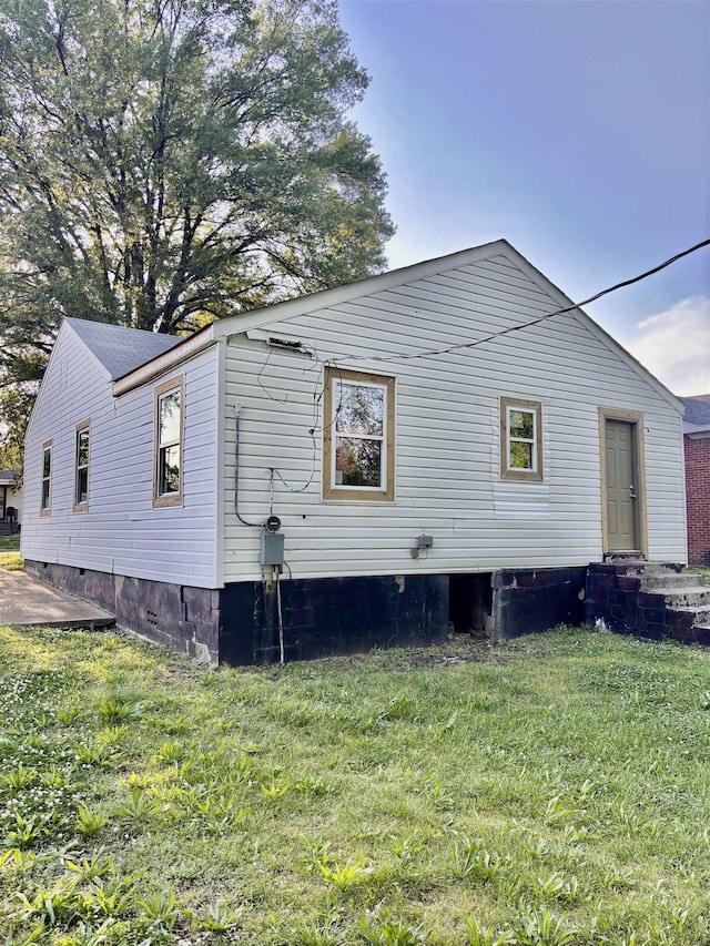 view of side of property featuring a lawn and crawl space
