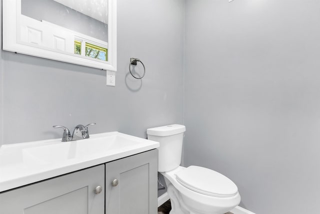 bathroom with baseboards, vanity, and toilet