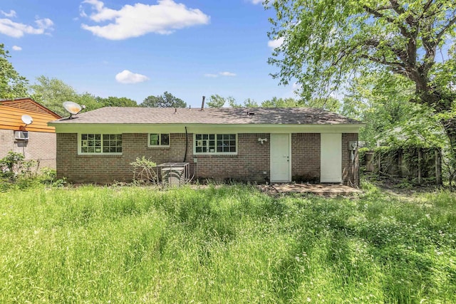 rear view of house featuring brick siding and fence
