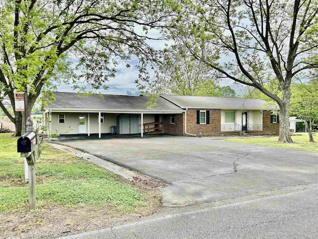 single story home with an attached carport, driveway, a front lawn, and brick siding