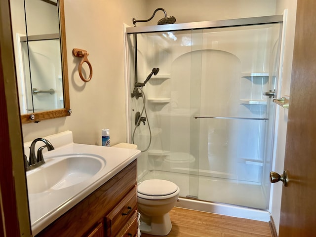 full bath with vanity, toilet, wood finished floors, and a stall shower