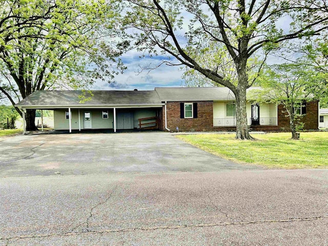 ranch-style home featuring brick siding, aphalt driveway, a front yard, and an attached carport