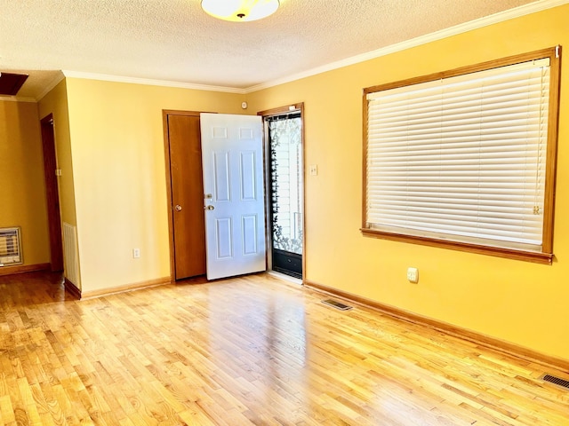 unfurnished room featuring baseboards, ornamental molding, a textured ceiling, and wood finished floors