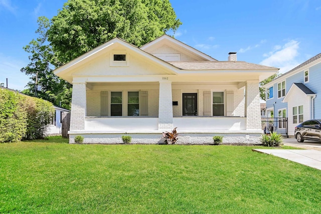 view of front of home featuring covered porch, brick siding, and a front yard