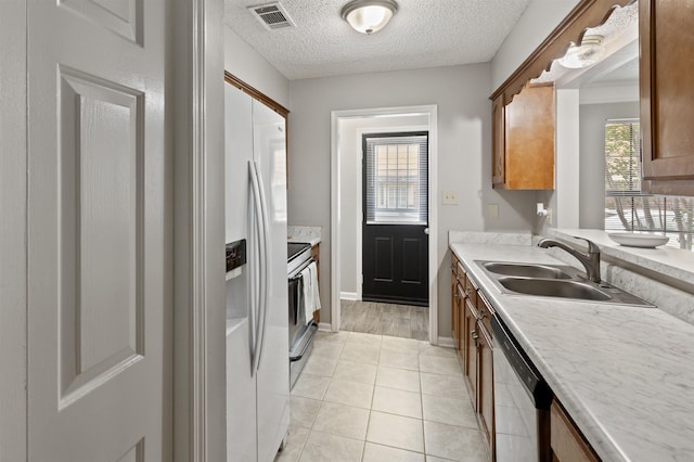 kitchen with visible vents, appliances with stainless steel finishes, brown cabinets, a sink, and light countertops