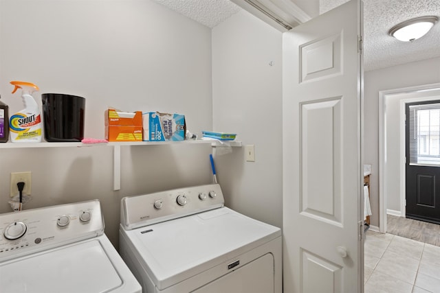 washroom featuring light tile patterned floors, laundry area, a textured ceiling, and washer and clothes dryer