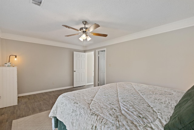 bedroom with a textured ceiling, ornamental molding, baseboards, visible vents, and dark wood-style floors