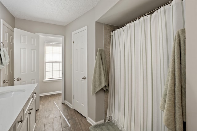 full bathroom with a textured ceiling, wood finished floors, baseboards, vanity, and a shower with shower curtain
