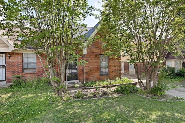 view of front of home featuring brick siding and a front lawn