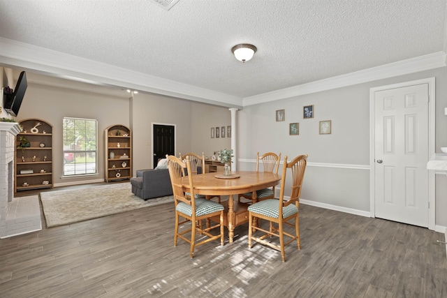 dining area featuring ornate columns, a textured ceiling, and wood finished floors
