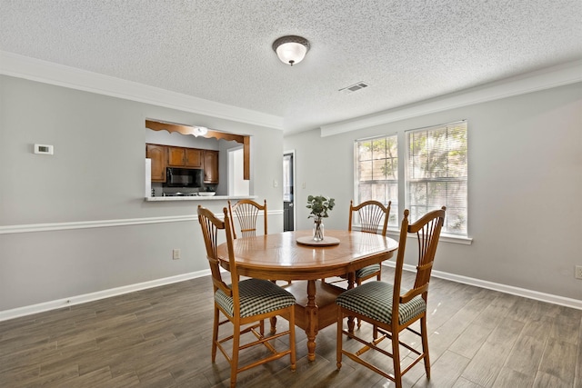 dining space featuring wood finished floors, baseboards, a textured ceiling, and visible vents