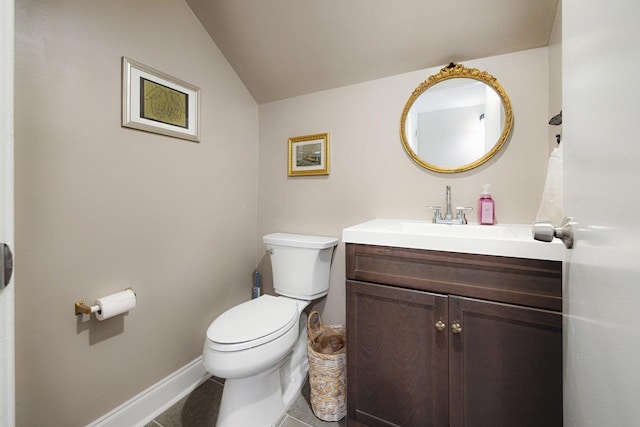 bathroom featuring vanity, toilet, tile patterned floors, baseboards, and vaulted ceiling