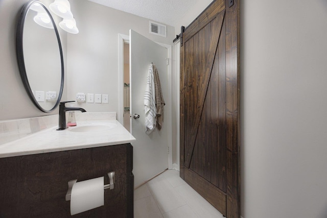 bathroom with vanity, a textured ceiling, tile patterned floors, and visible vents