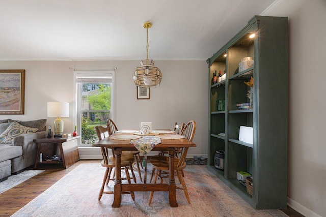 dining room with baseboards, ornamental molding, and wood finished floors
