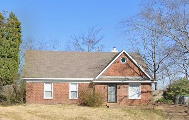 view of front of home featuring brick siding, a chimney, and a front yard
