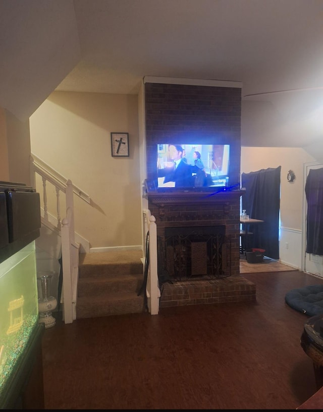 living area with baseboards, stairs, wood finished floors, and vaulted ceiling
