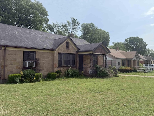 single story home with a front lawn, stone siding, cooling unit, roof with shingles, and a chimney