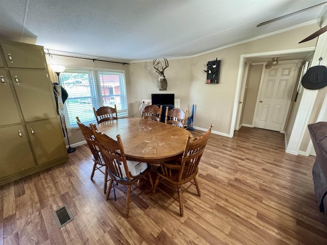 dining space featuring visible vents, light wood-style flooring, crown molding, and baseboards