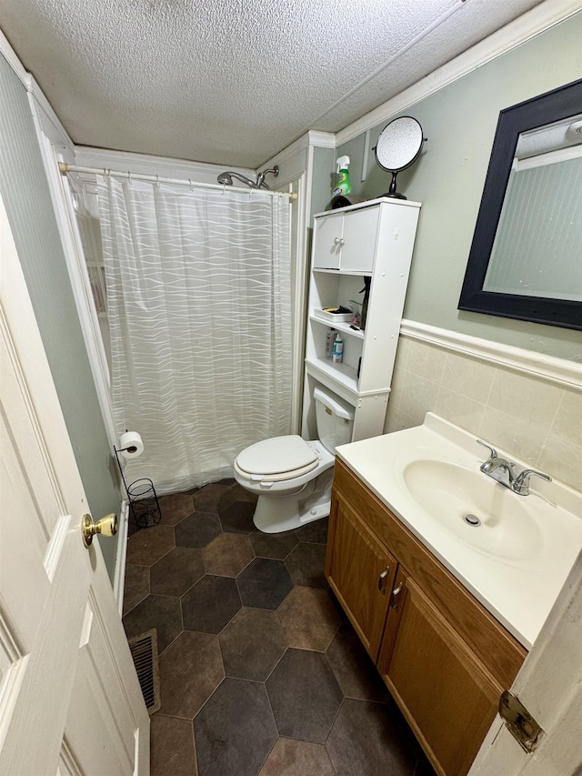 bathroom with visible vents, vanity, curtained shower, toilet, and a textured ceiling