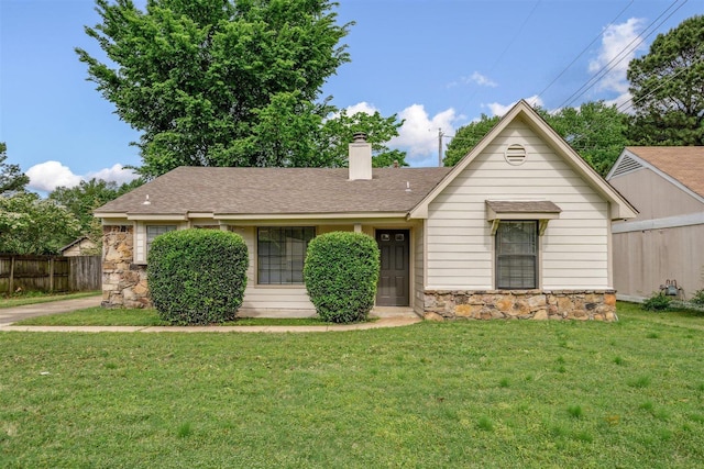 view of front of home featuring fence, a front yard, stone siding, a chimney, and a shingled roof