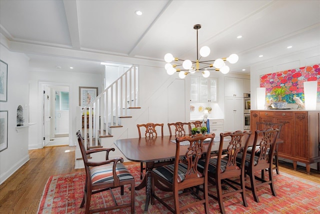 dining area with light wood-style flooring, beam ceiling, a chandelier, and stairway