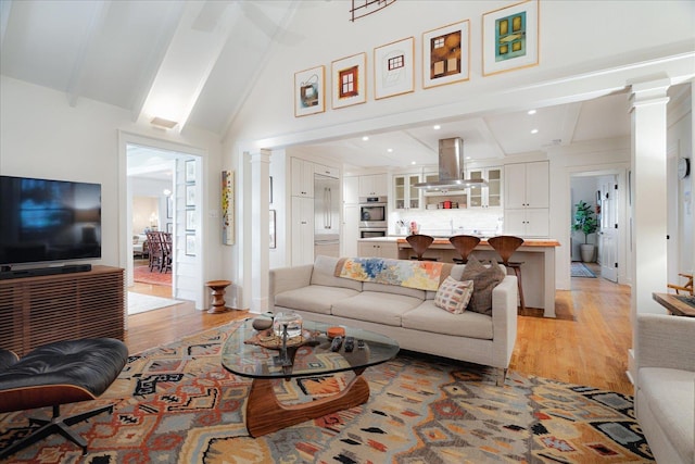 living room featuring ornate columns, lofted ceiling with beams, recessed lighting, and light wood-type flooring