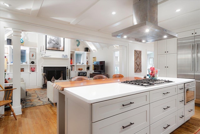 kitchen with island exhaust hood, a center island, beam ceiling, stainless steel appliances, and light wood-style flooring