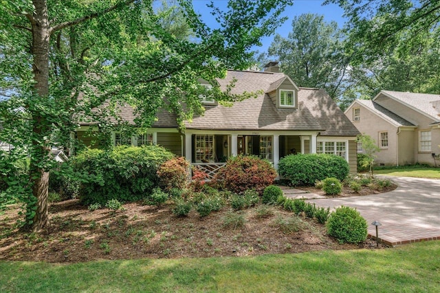 view of front of home featuring a chimney, a shingled roof, and a front lawn